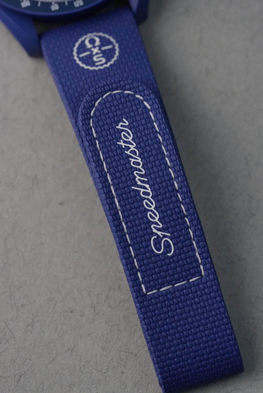 Blue strap with 'Speedmaster' text on a gray background