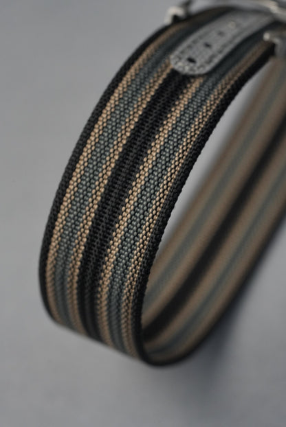 Close-up of a striped belt with a metal buckle on a gray background