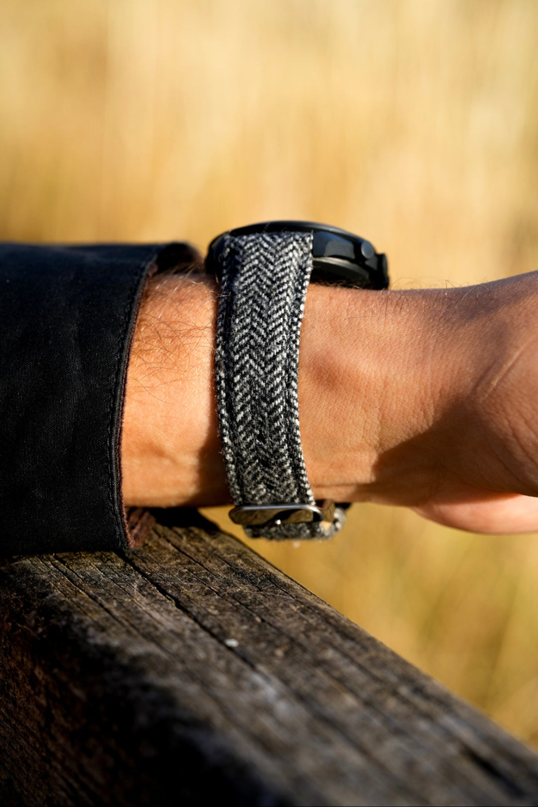 Person wearing a black smartwatch with a textured band on a wooden surface