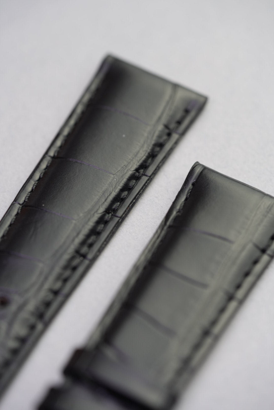 Close-up of alligator grain texture and stitching near lugs on black leather strap
