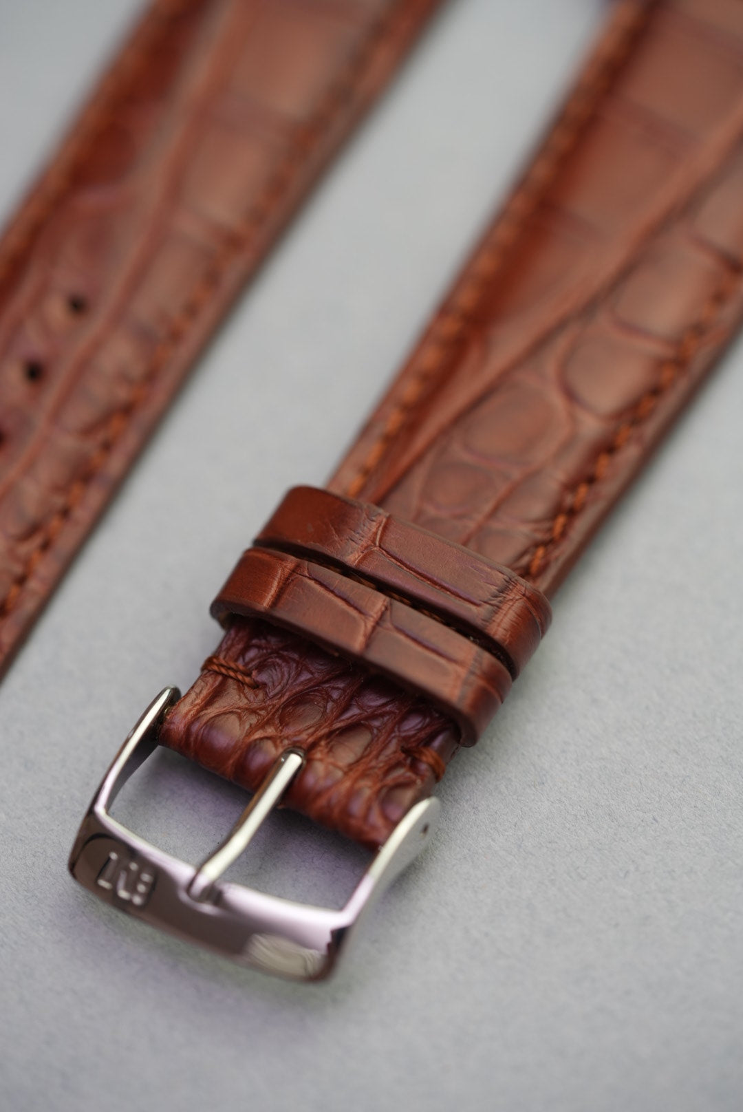 Close-up of keeper loops and texture on alligator embossed brown leather watch strap