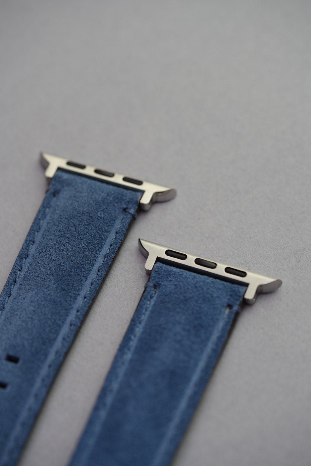 Close-up of stainless steel Apple Watch connectors on blue suede leather strap – fits all series