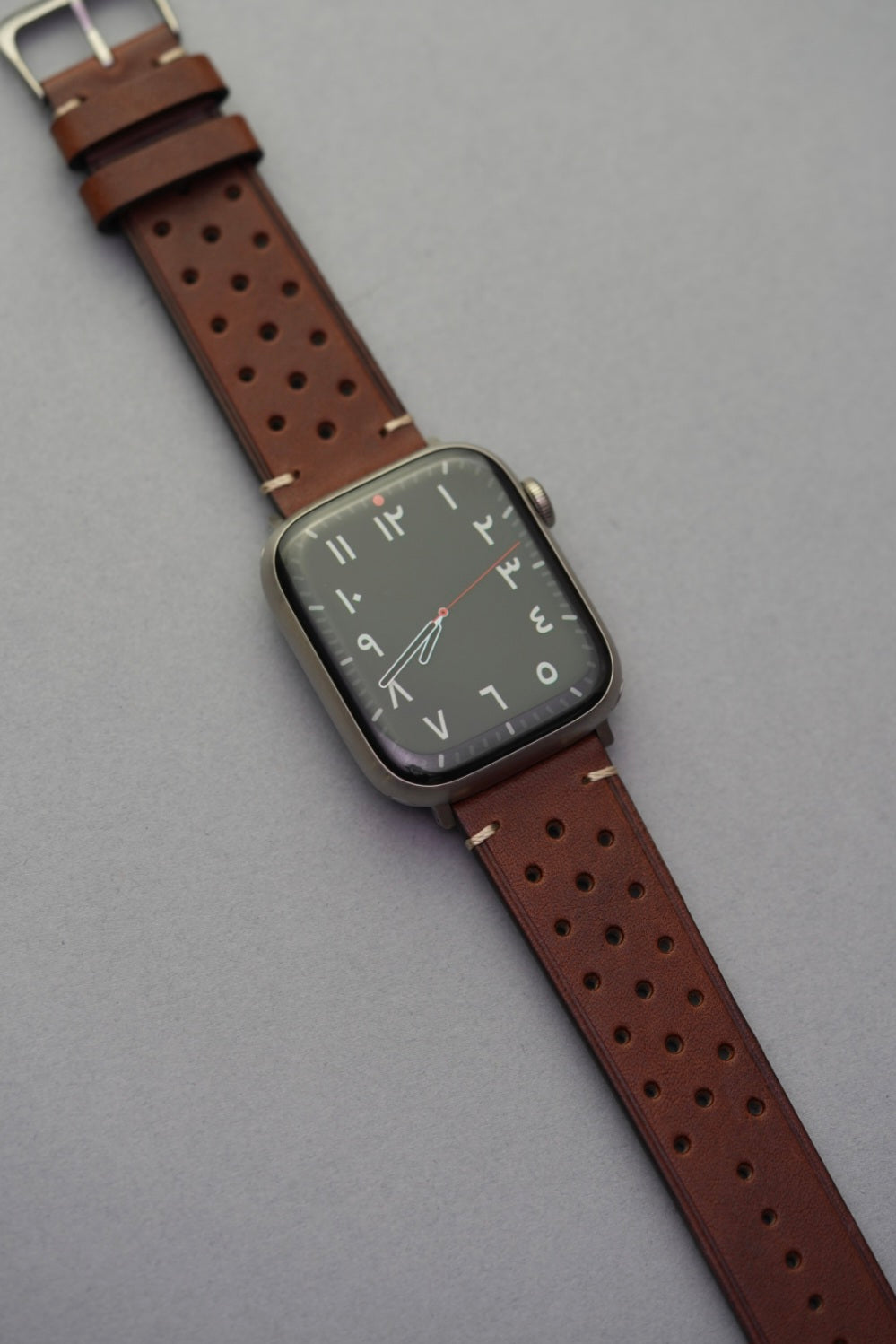 Brown perforated leather strap fitted to Apple Watch in full length view