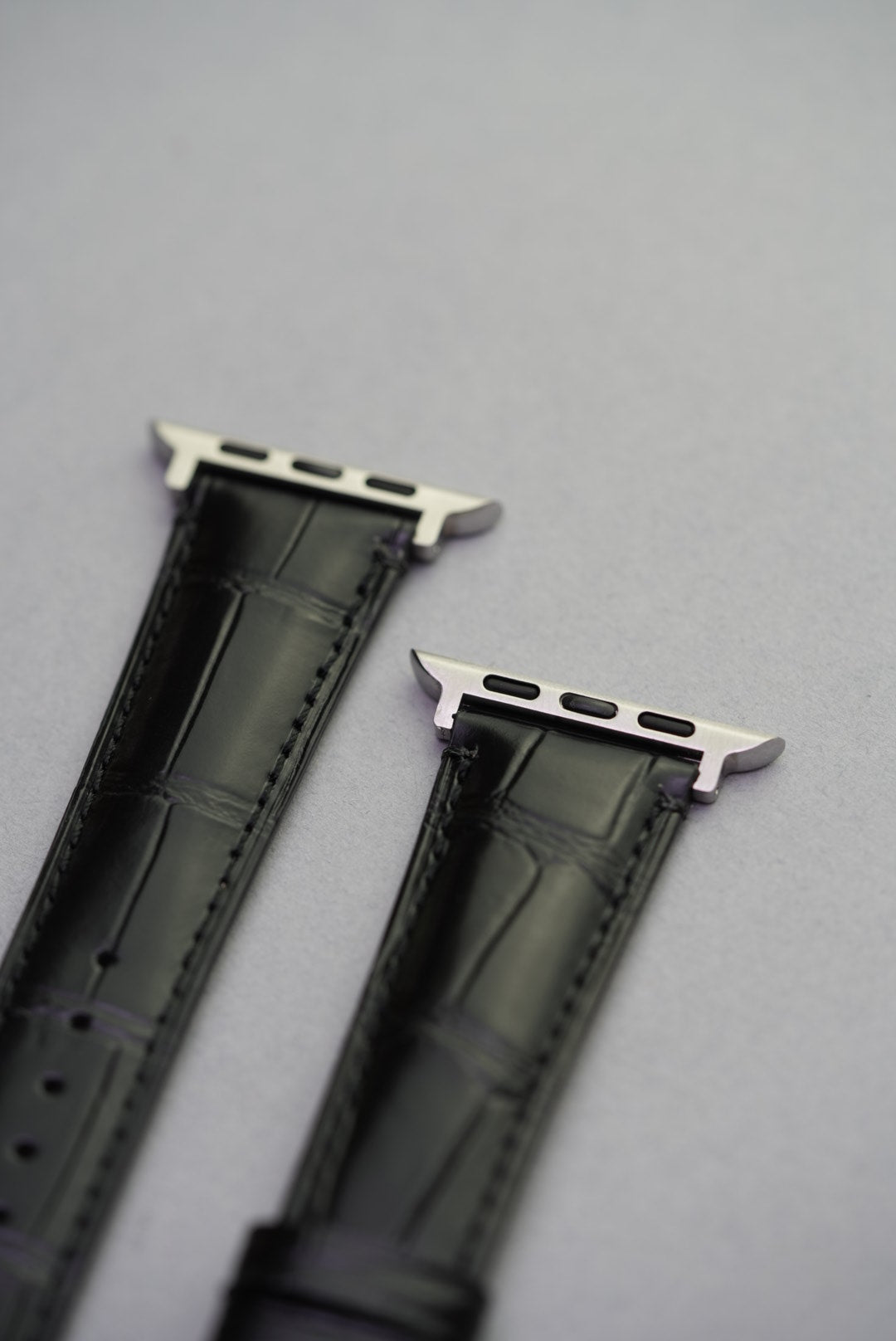 Upper lug detail of Apple Watch strap in black alligator-style calfskin leather.