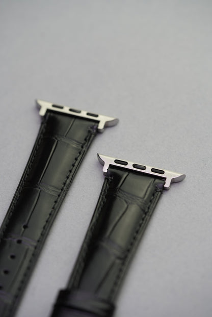 Upper lug detail of Apple Watch strap in black alligator-style calfskin leather.