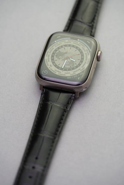 Upper lug detail of Apple Watch strap in black alligator-style calfskin leather.