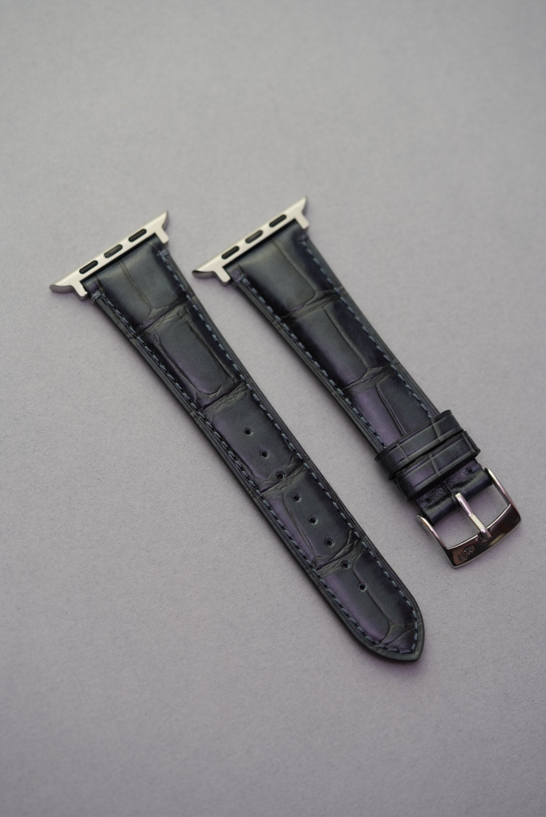 Top-down view of black embossed alligator leather strap for Apple Watch, showcasing detailed grain and stitching.