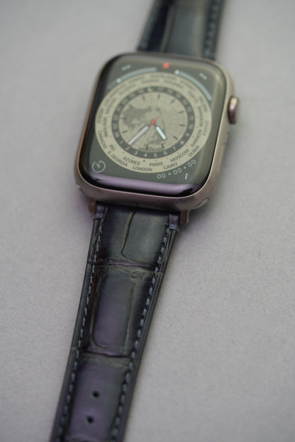 Side angle of black embossed alligator calfskin leather strap fitted to Apple Watch, showing curvature and texture.