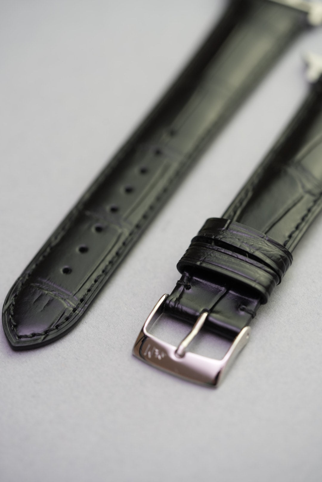 Detailed shot of black calfskin embossed strap showing grain texture and polished buckle.