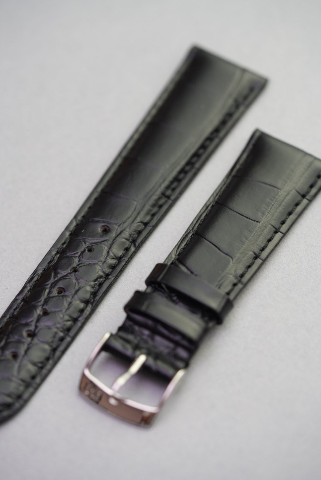 Front view of black alligator style leather strap with silver-tone buckle