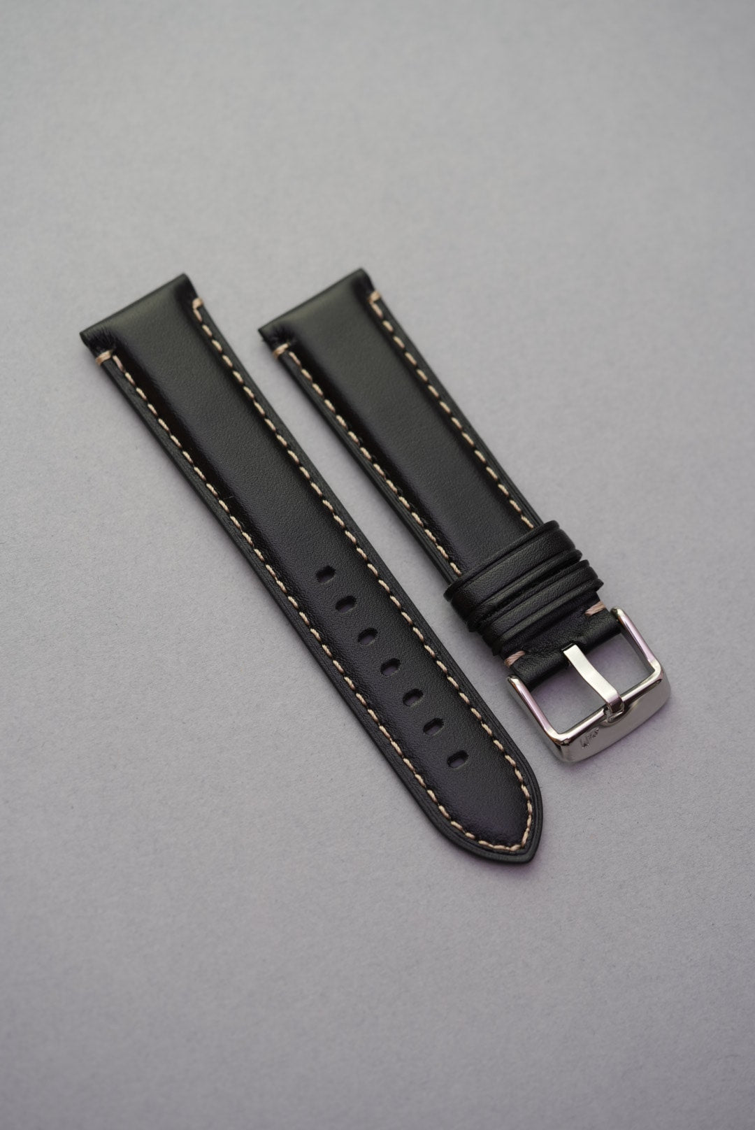 Black leather watch strap with cream stitching laid flat – ideal for strap replacement