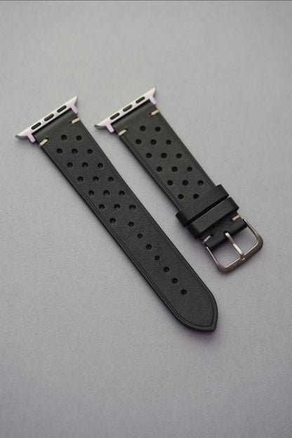 Perforated black leather strap with adapters for Apple Watch – flat lay view