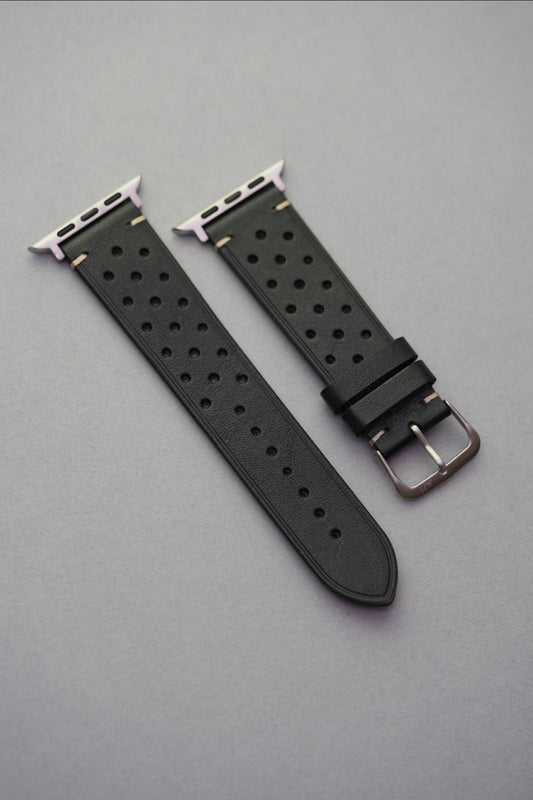 Perforated black leather strap with adapters for Apple Watch – flat lay view