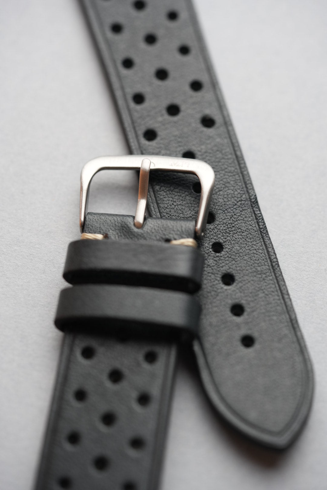 Detailed close-up of black perforated strap with stainless steel buckle
