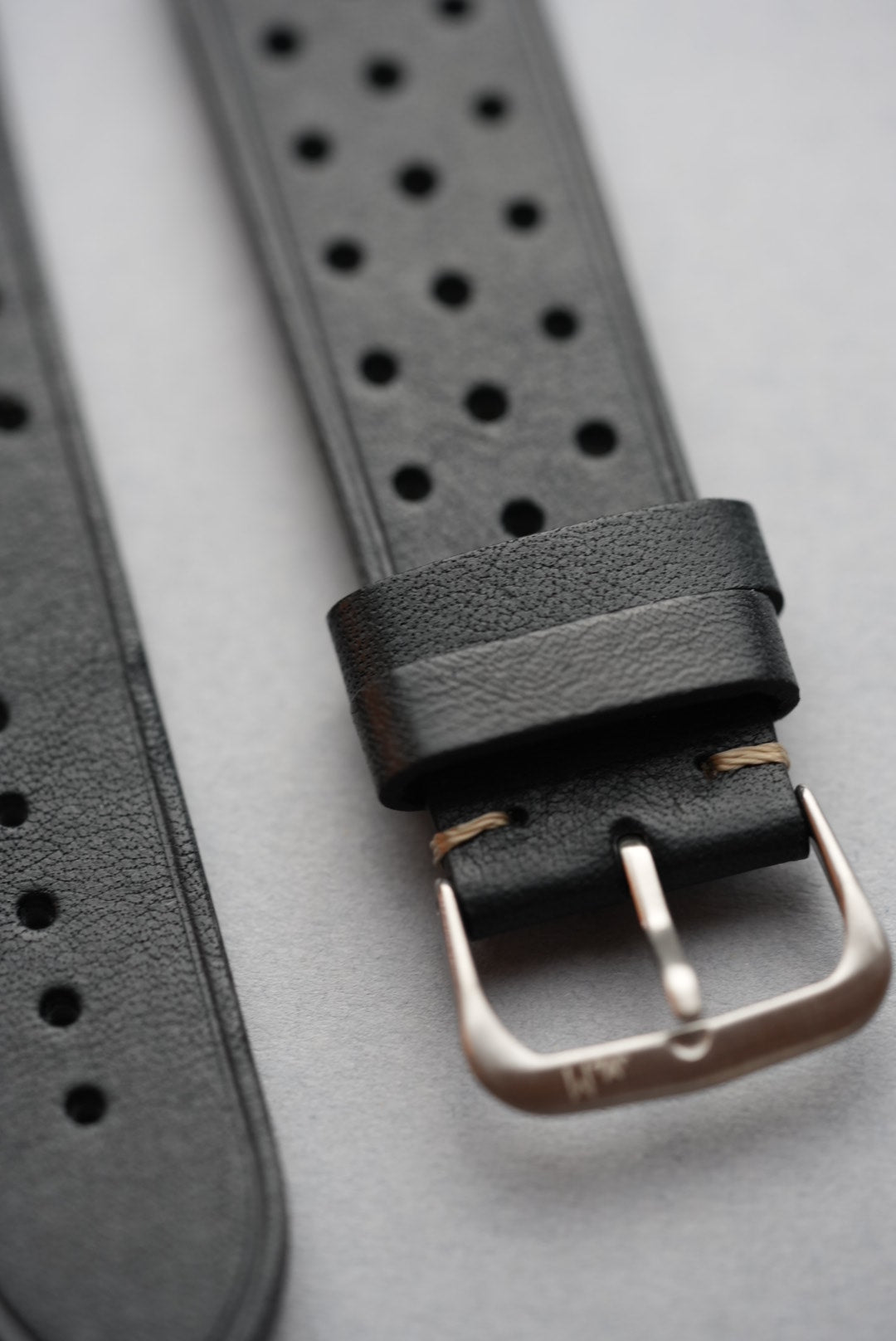 Detailed close-up of black perforated strap with stainless steel buckle