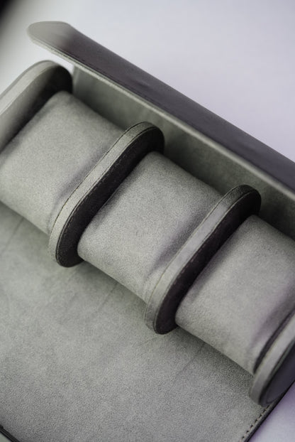 Top-down view of the open black watch roll showing three empty suede-lined compartments.