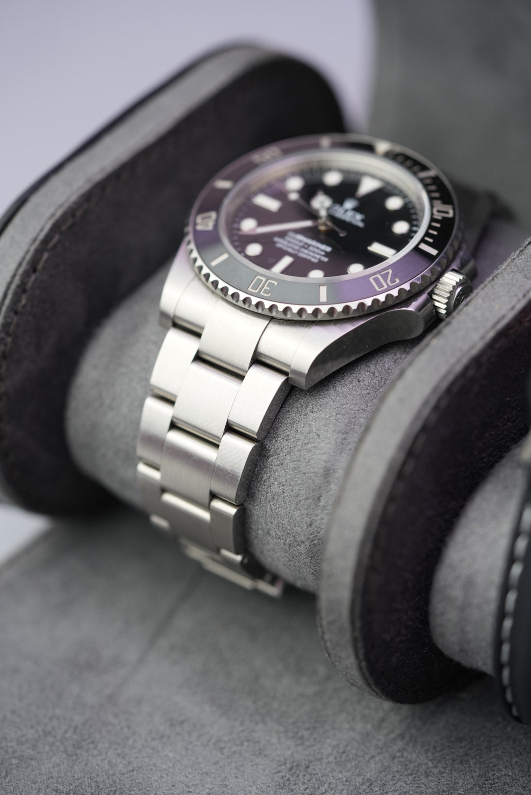 Close-up of Rolex Submariner on grey suede cushion inside the open black watch roll.