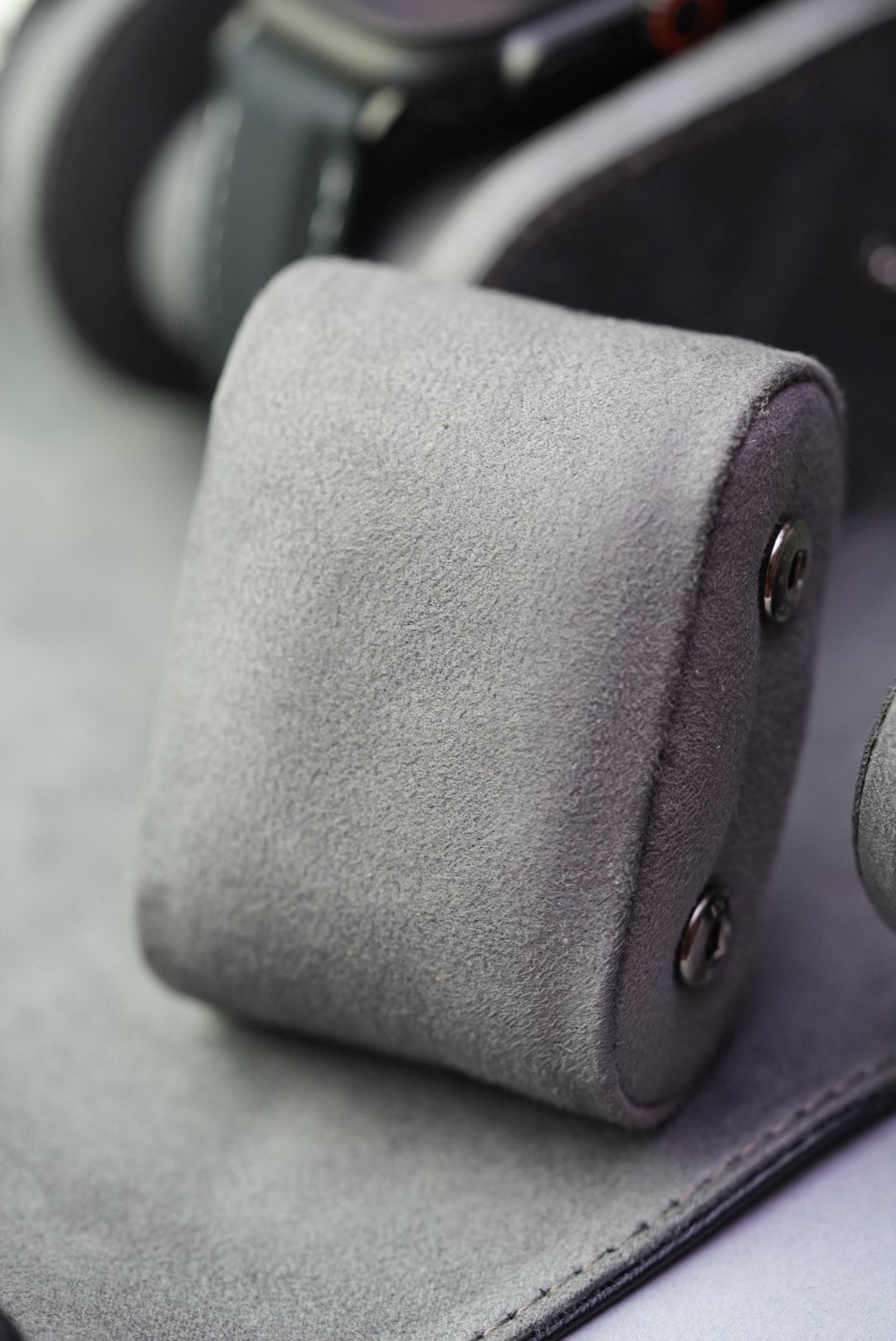 Close-up of one suede cushion, highlighting the soft textured material and snap fasteners.