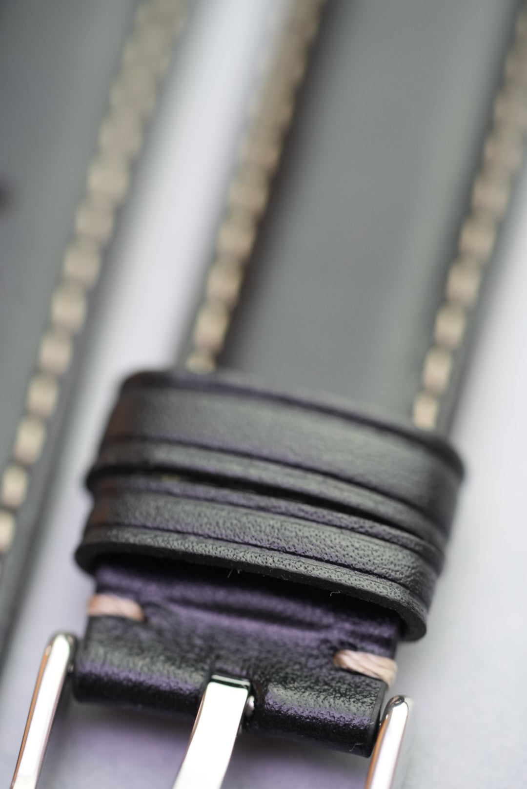 Close-up of keeper loops and cream stitching on black leather strap