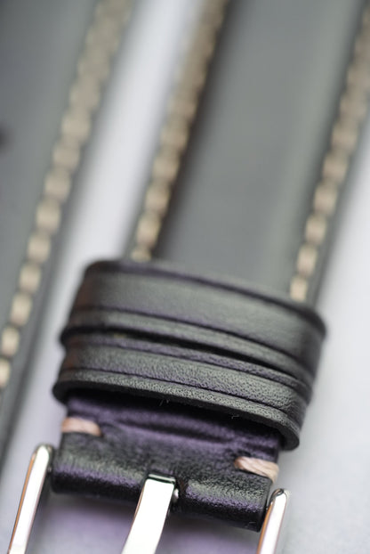 Close-up of keeper loops and cream stitching on black leather strap