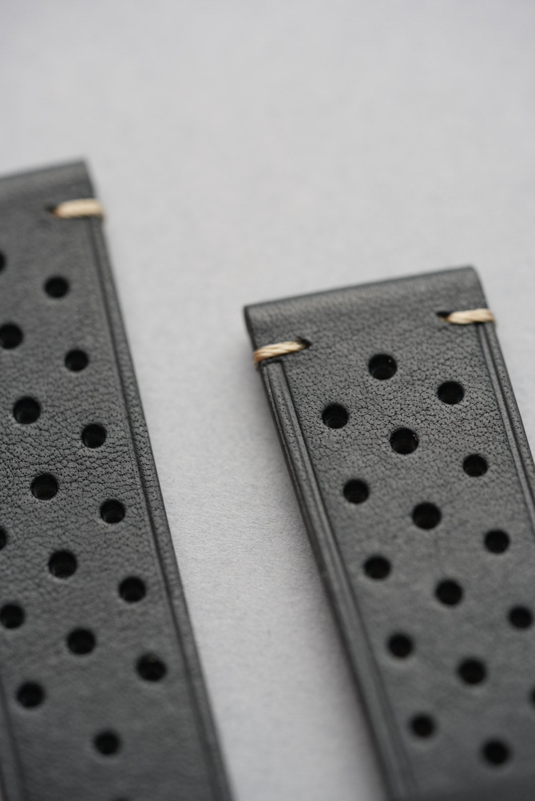 Close-up top section of black perforated leather watch strap with detailed stitching