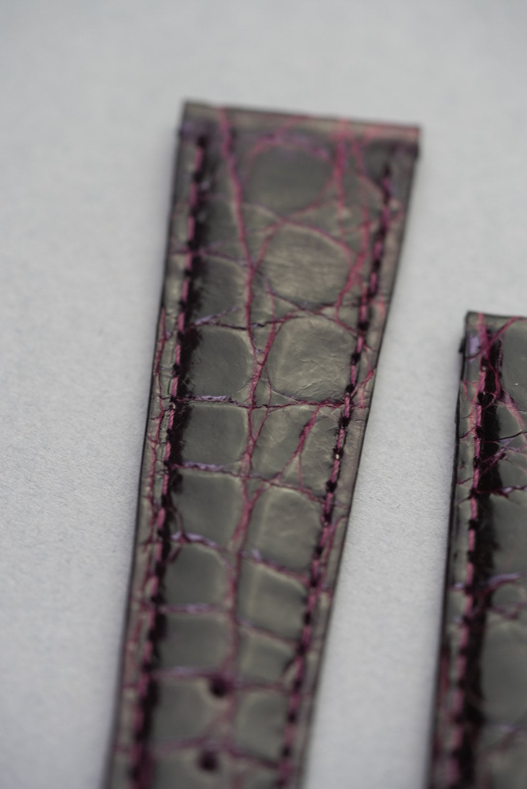Detailed look at Bordeaux crocodile grain and contrast stitching, showcasing the natural scale variation and shine.