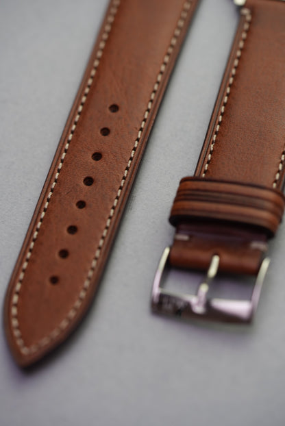 Detail shot of fine grain texture and contrast stitching on brown leather strap for Apple Watch