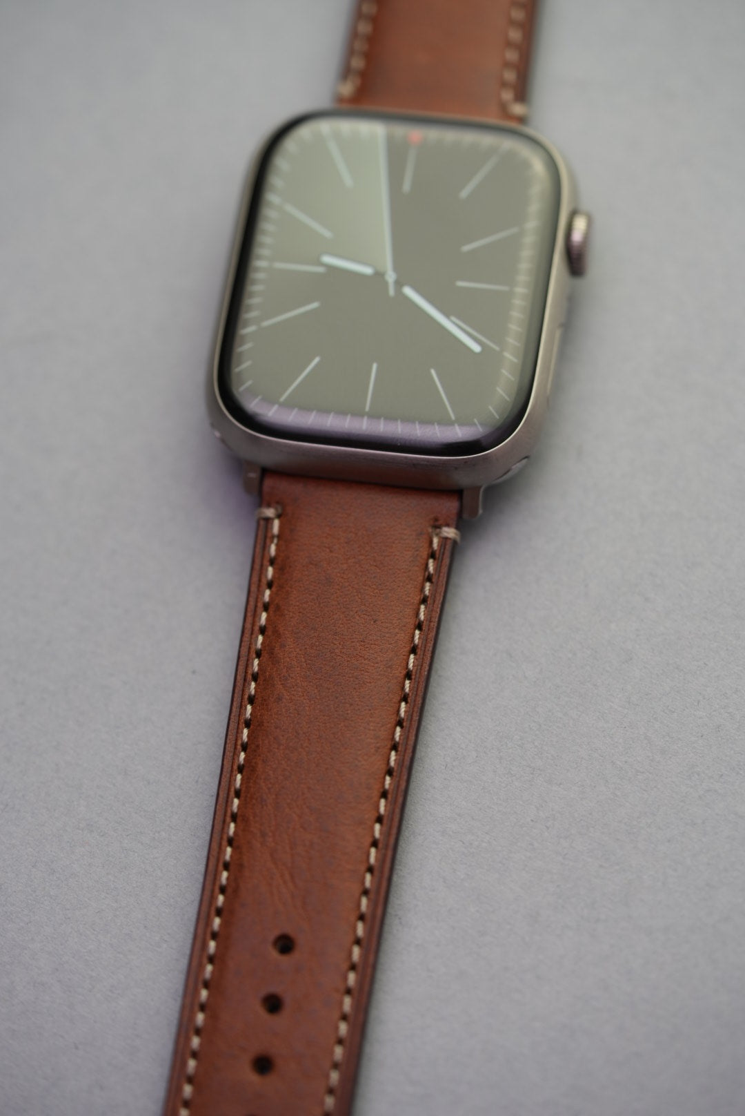 Detail shot of fine grain texture and contrast stitching on brown leather strap for Apple Watch