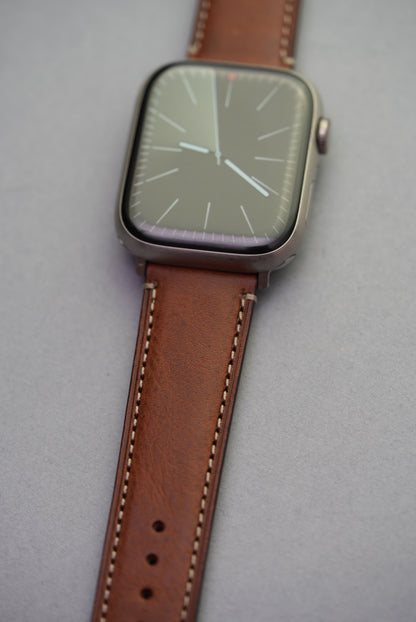 Detail shot of fine grain texture and contrast stitching on brown leather strap for Apple Watch