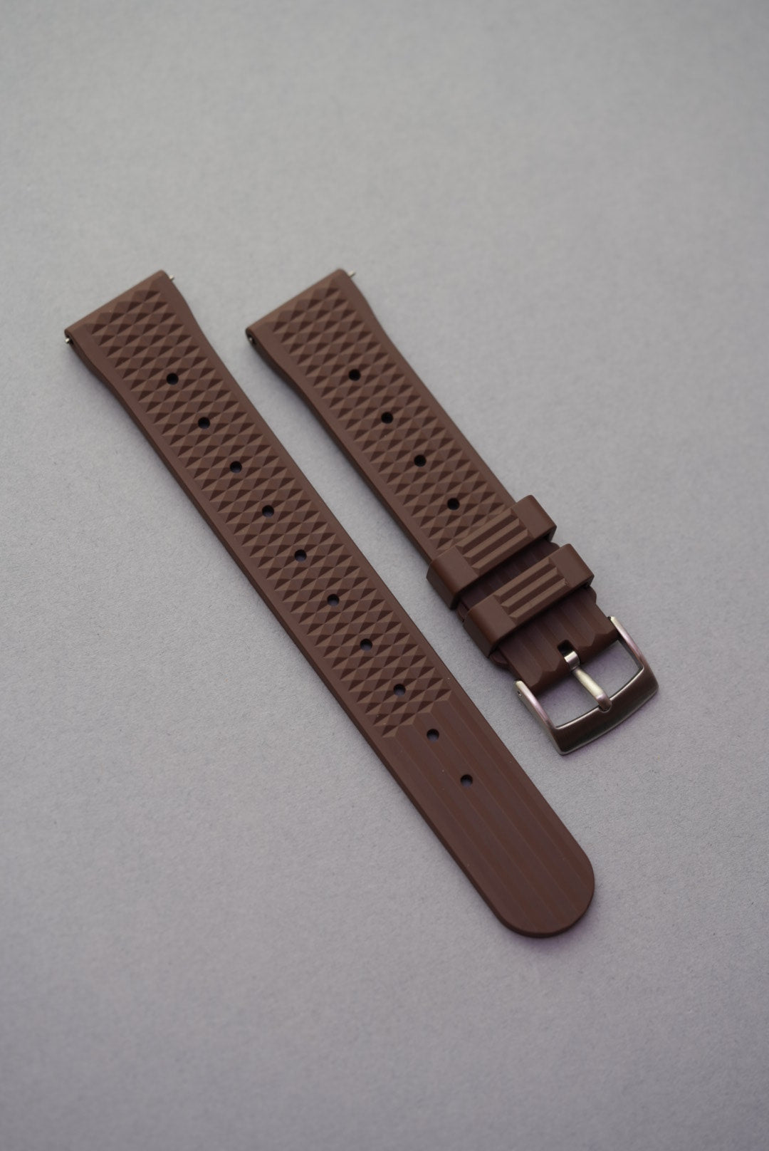Brown pyramid-textured FKM waffle strap for MoonSwatch with stainless steel buckle and secure curved fit.