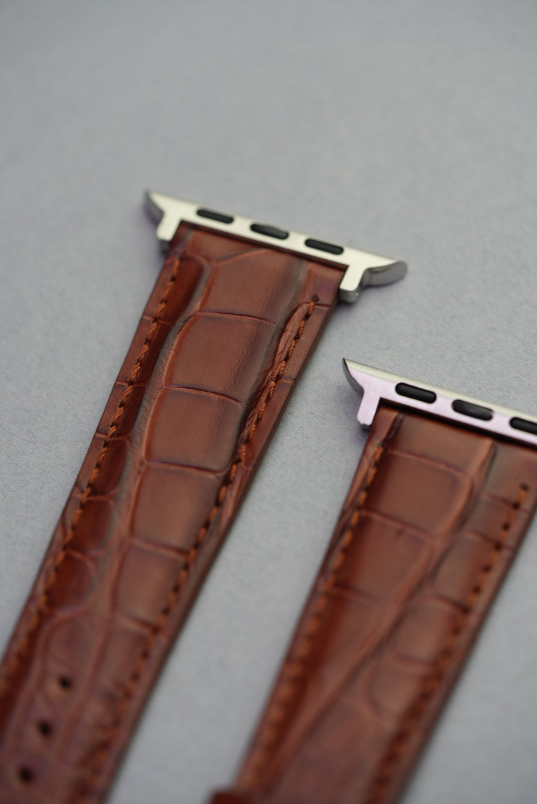 Detailed close-up of adapter fitment on brown alligator embossed strap for Apple Watch