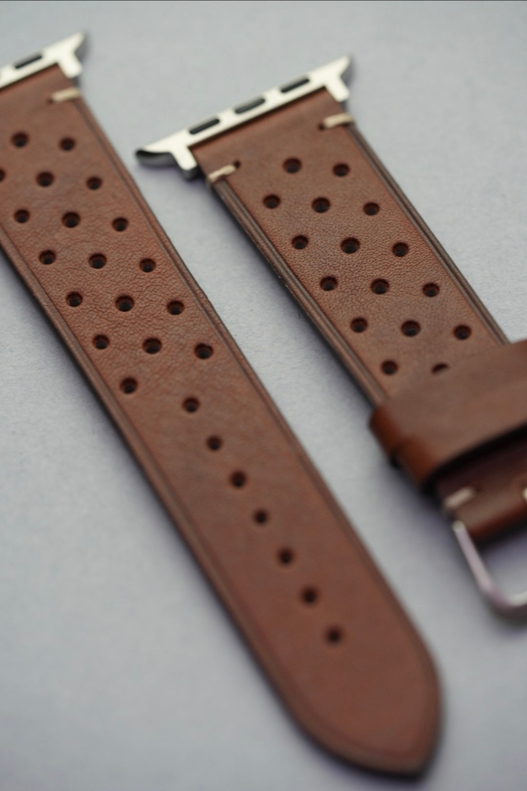 Angled view of perforated leather strap with Apple Watch adapters fitted
