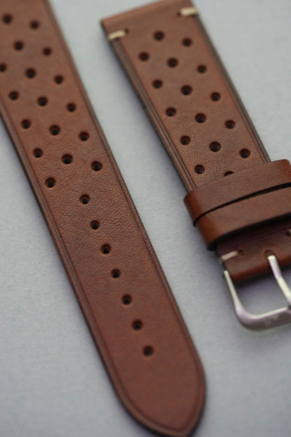 Close-up of brown leather strap and buckle with perforated holes