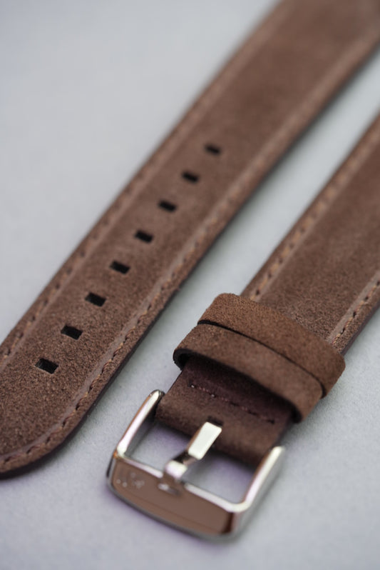 Close-up of brown suede watch strap showing stainless buckle and keeper loops