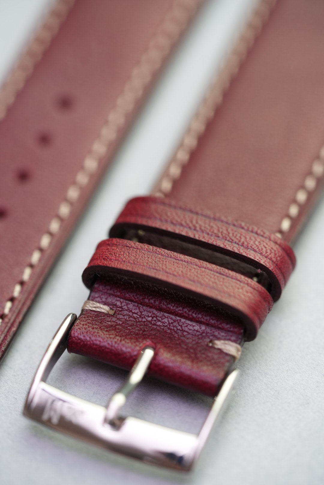 Detailed look at the hand-stitched loops and natural finish on the burgundy calfskin strap