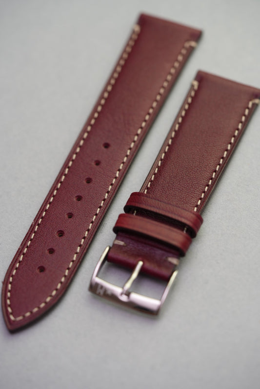 Front-facing view of the burgundy calfskin leather strap with natural grain and contrast stitching