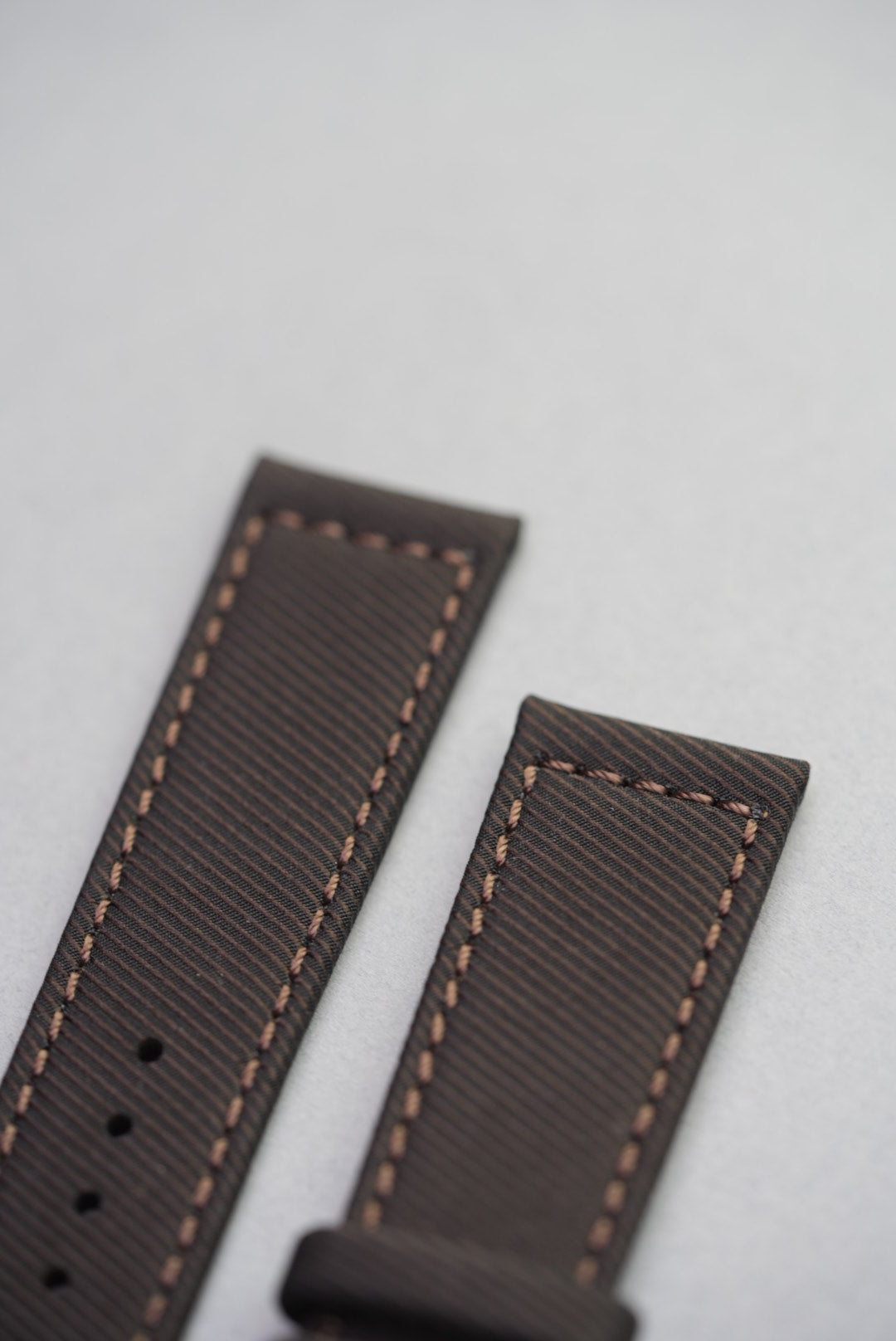 Detailed buckle close-up on the clay brown strap with matching loops and warm brown stitching.