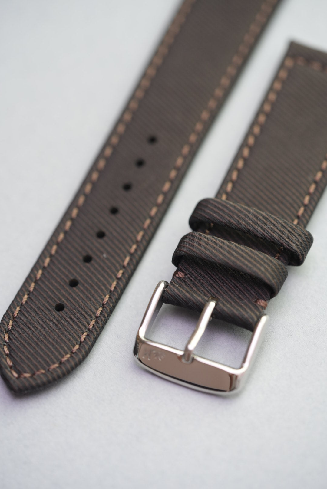 Angled view of clay brown strap with remborded edges and durable woven finish.