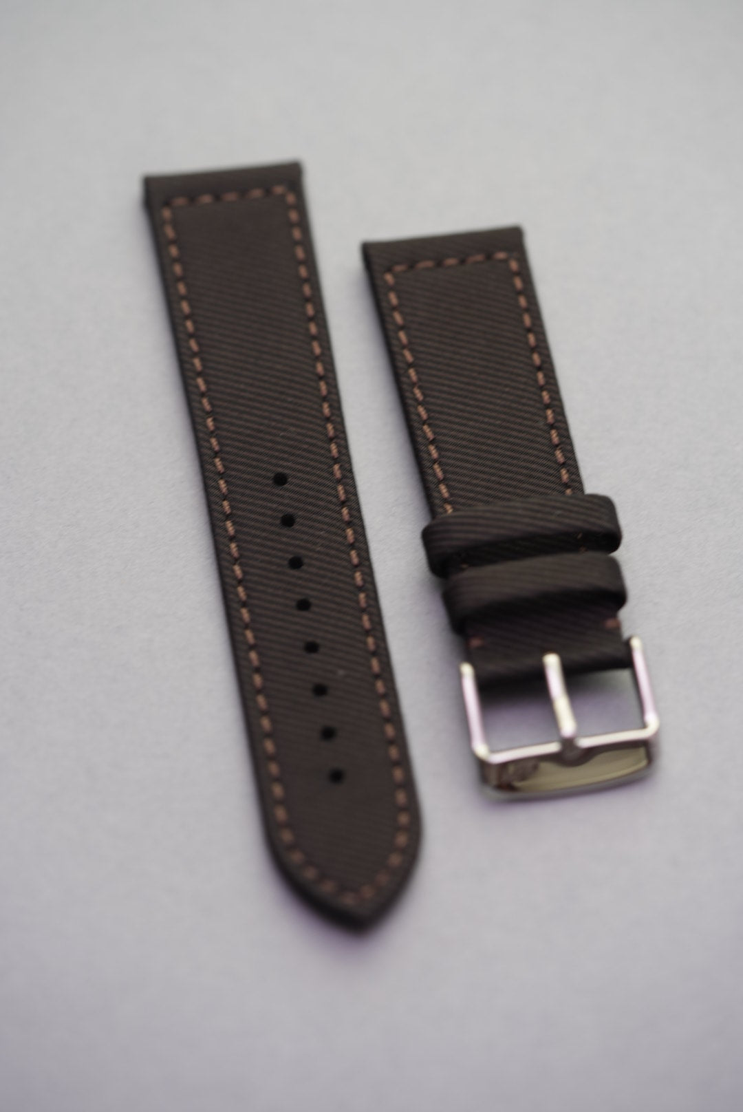 Full flat lay of the clay brown fabric strap with polished buckle, designed for classic and modern watches.