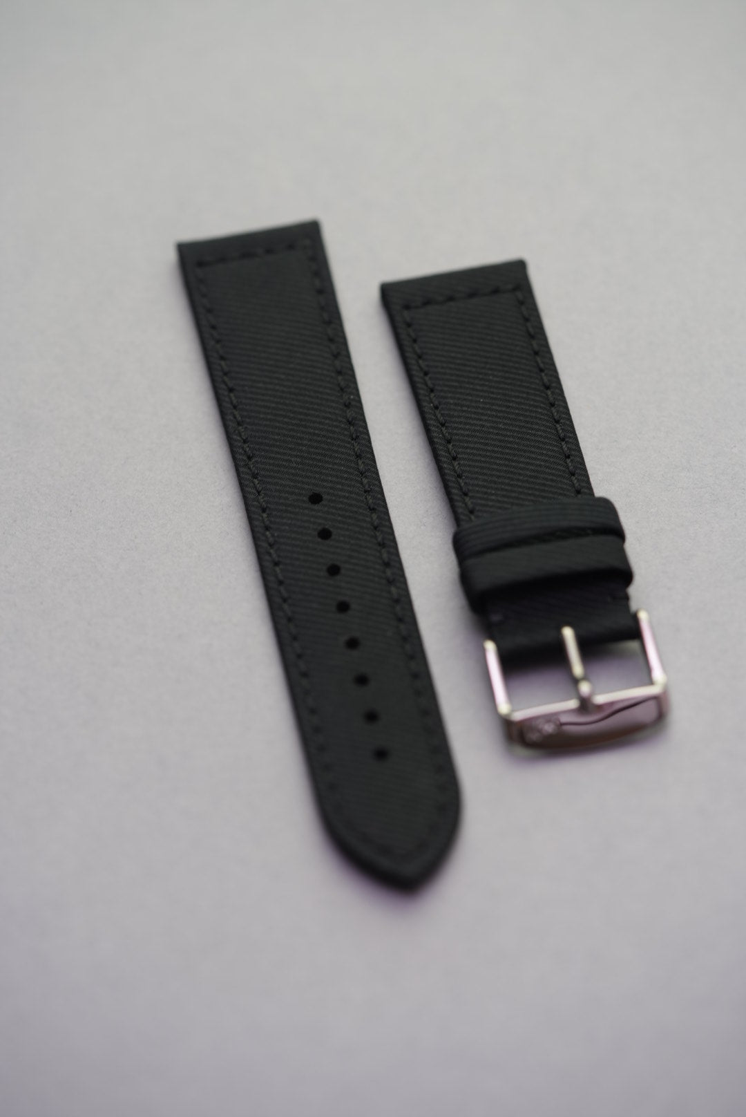Flat lay of the Coal Black strap made from recycled gabardine, showcasing polished hardware and clean edge finishing.