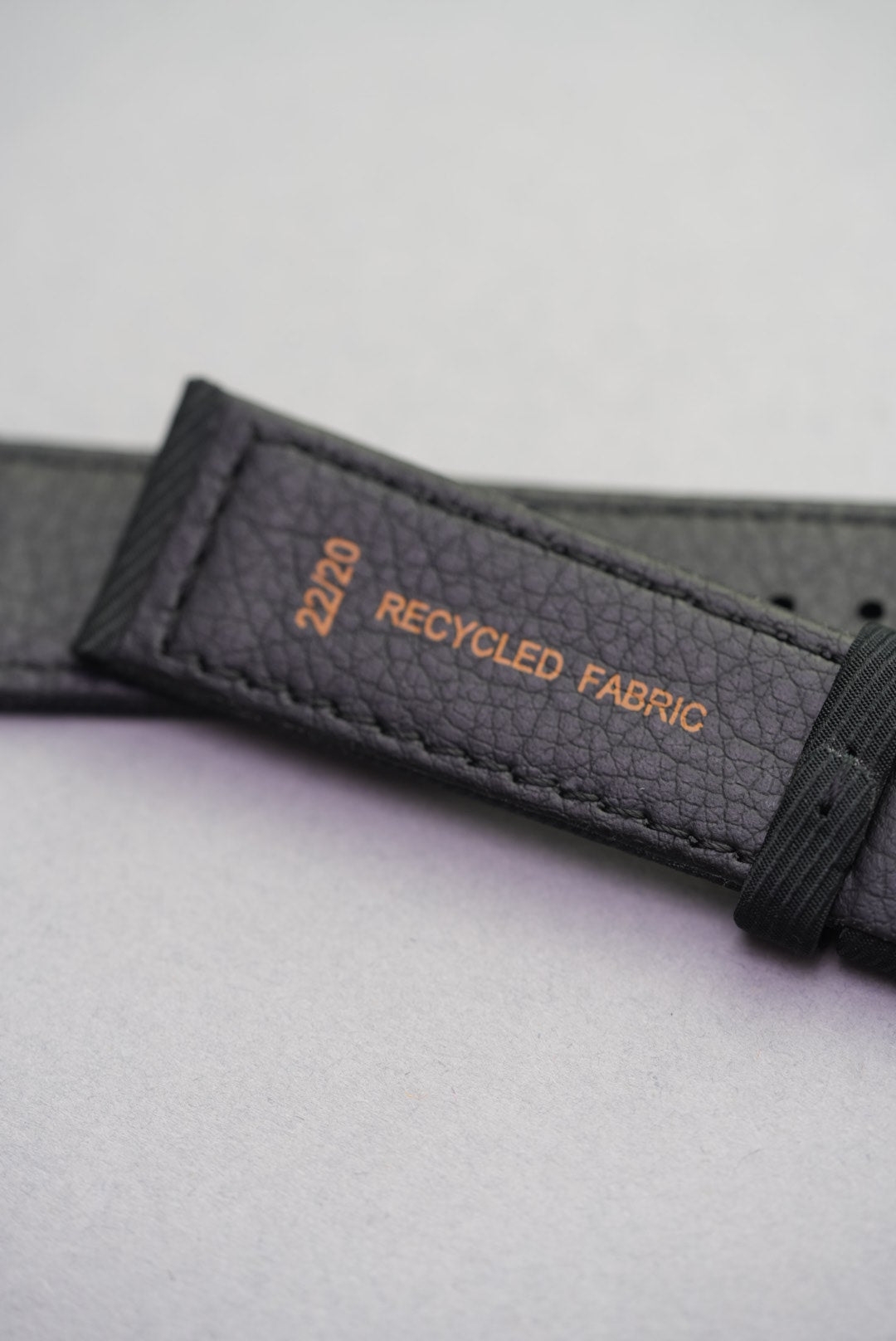 Underside view of the Coal Black recycled fabric strap showing 22/20 size and recycled material stamp with textured black lining.