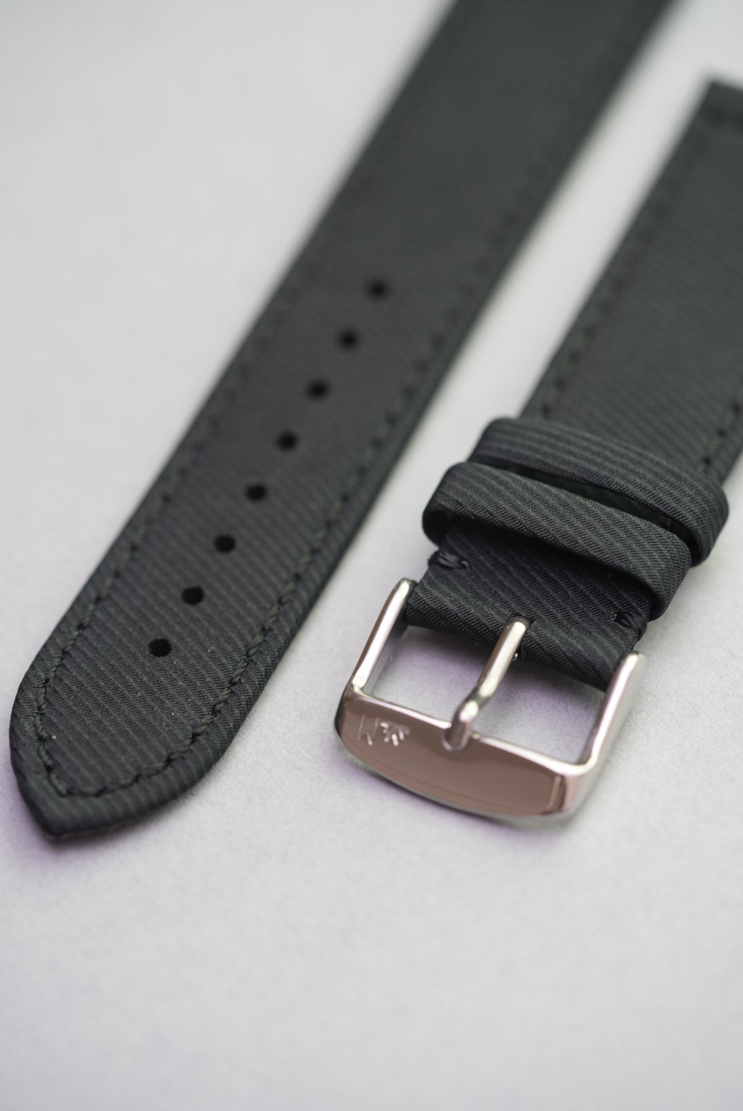 Close-up of the Coal Black gabardine strap with brushed buckle, double loops and subtle grain detail.