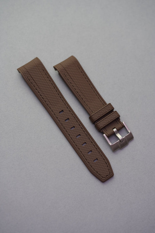 Chocolate brown curved rubber woven strap for MoonSwatch with tonal stitching and brushed steel buckle.
