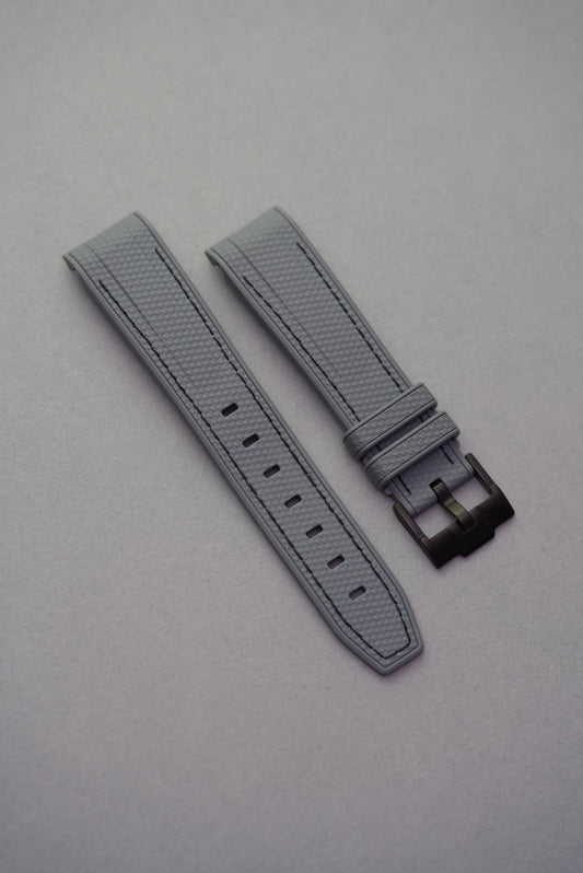 Dark grey curved-end MoonSwatch strap with black stitching, woven texture and matching black buckle.