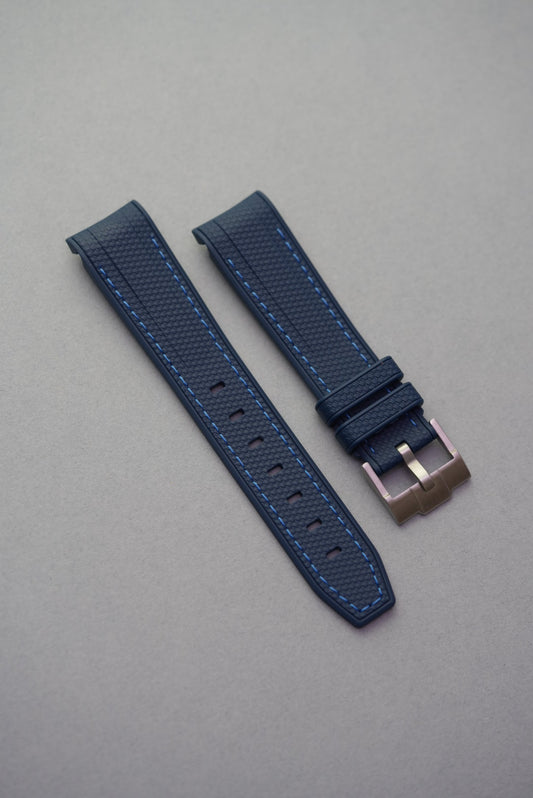 Woven navy MoonSwatch rubber strap with blue stitching and curved end links, designed to fit MoonSwatch models securely.