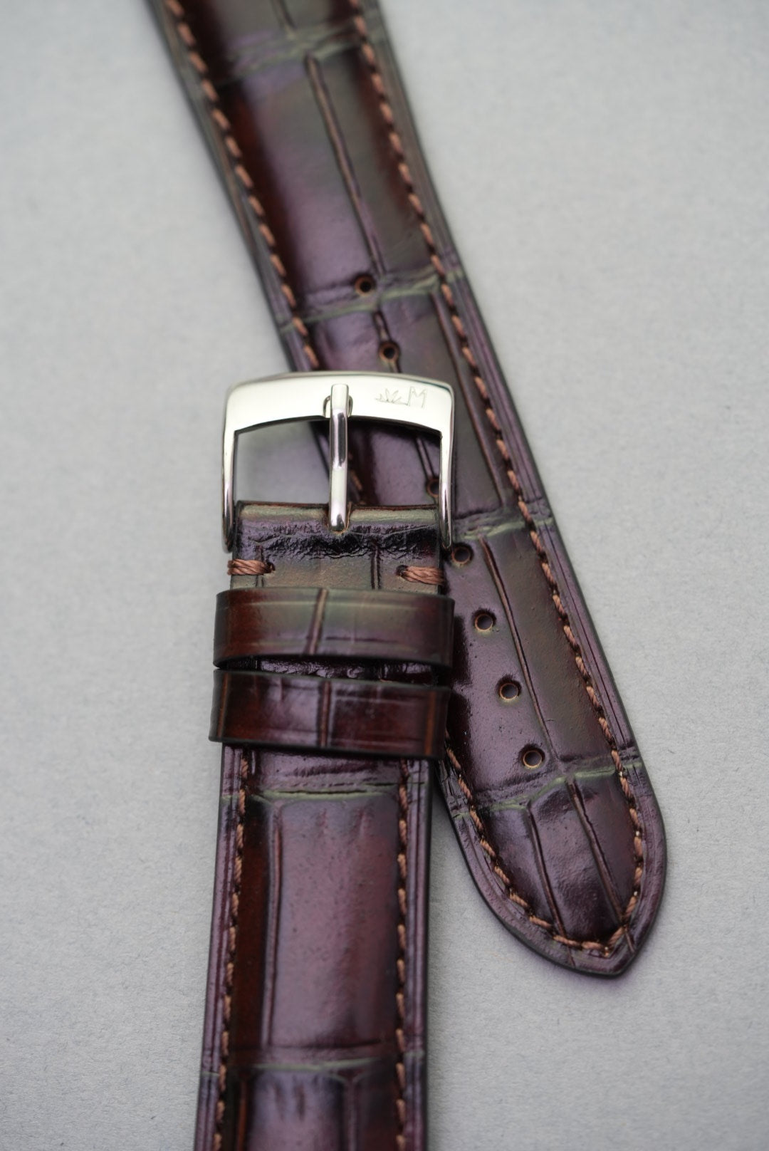  Close-up of the dark brown alligator-style grain and double loop keepers on calfskin watch strap.