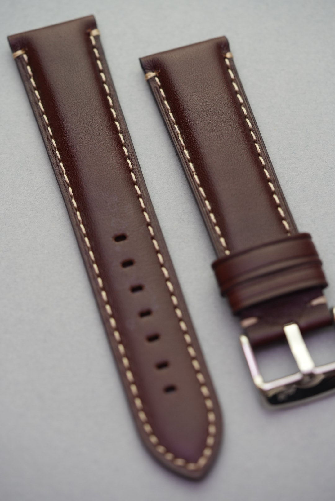 Angled view of dark brown leather strap showing cream contrast stitching and lug fit