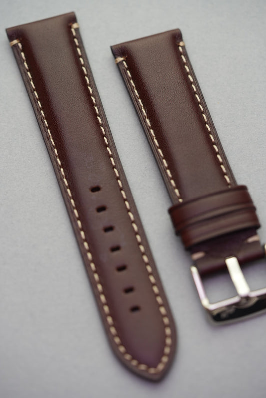 Angled view of dark brown leather strap showing cream contrast stitching and lug fit