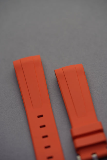Orange curved rubber strap laid flat with pre-installed stainless steel buckle and twin keepers