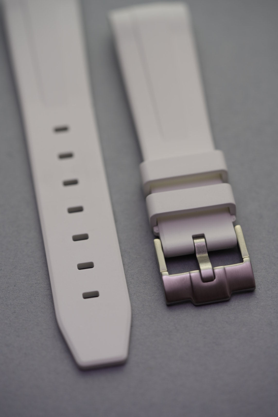White FKM curved rubber strap laid flat with stainless steel buckle, showing strap holes and detailed finishing.